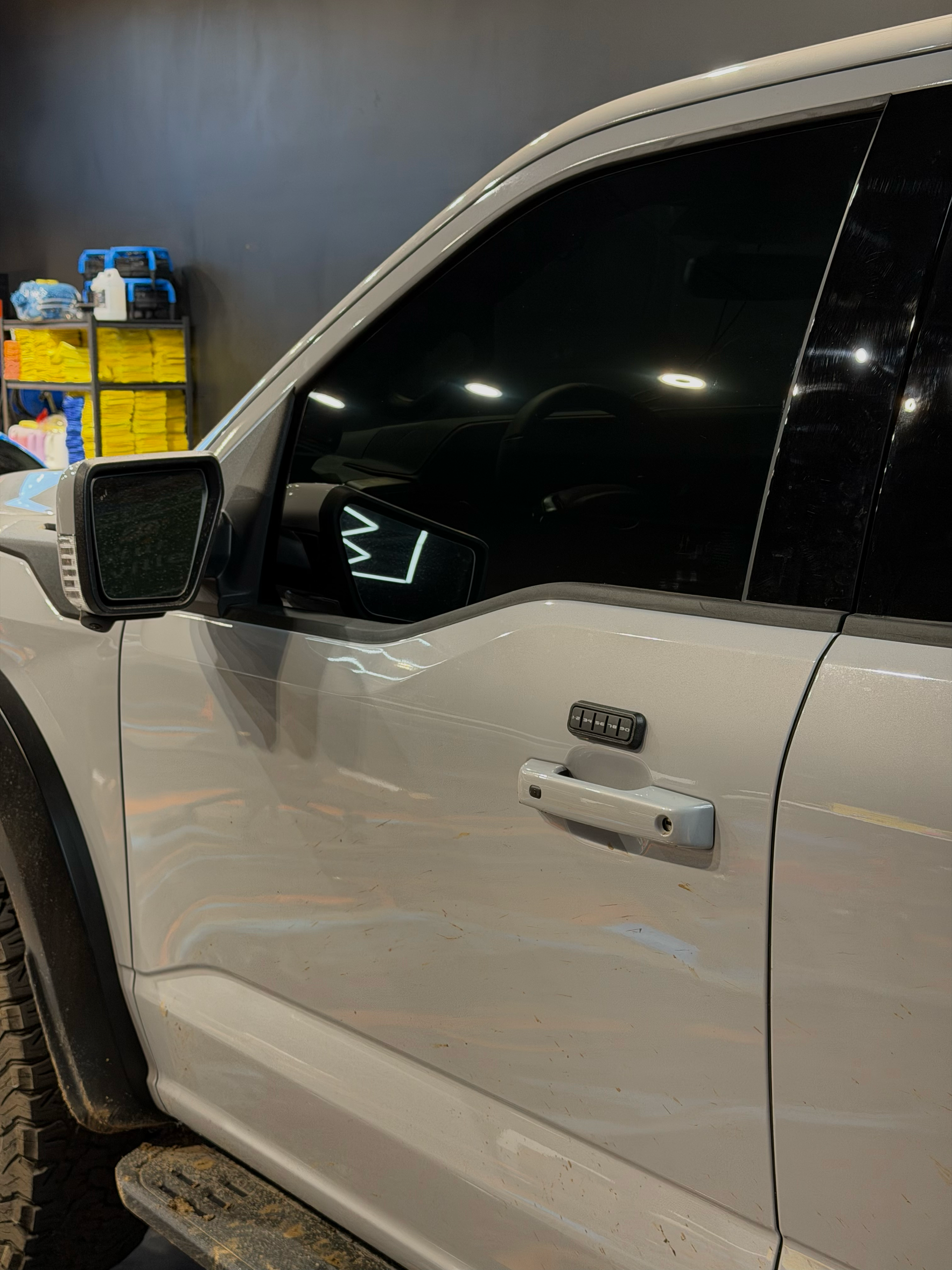 White Ford Raptor truck, tinted windows, black side mirror, Raptor door badge.