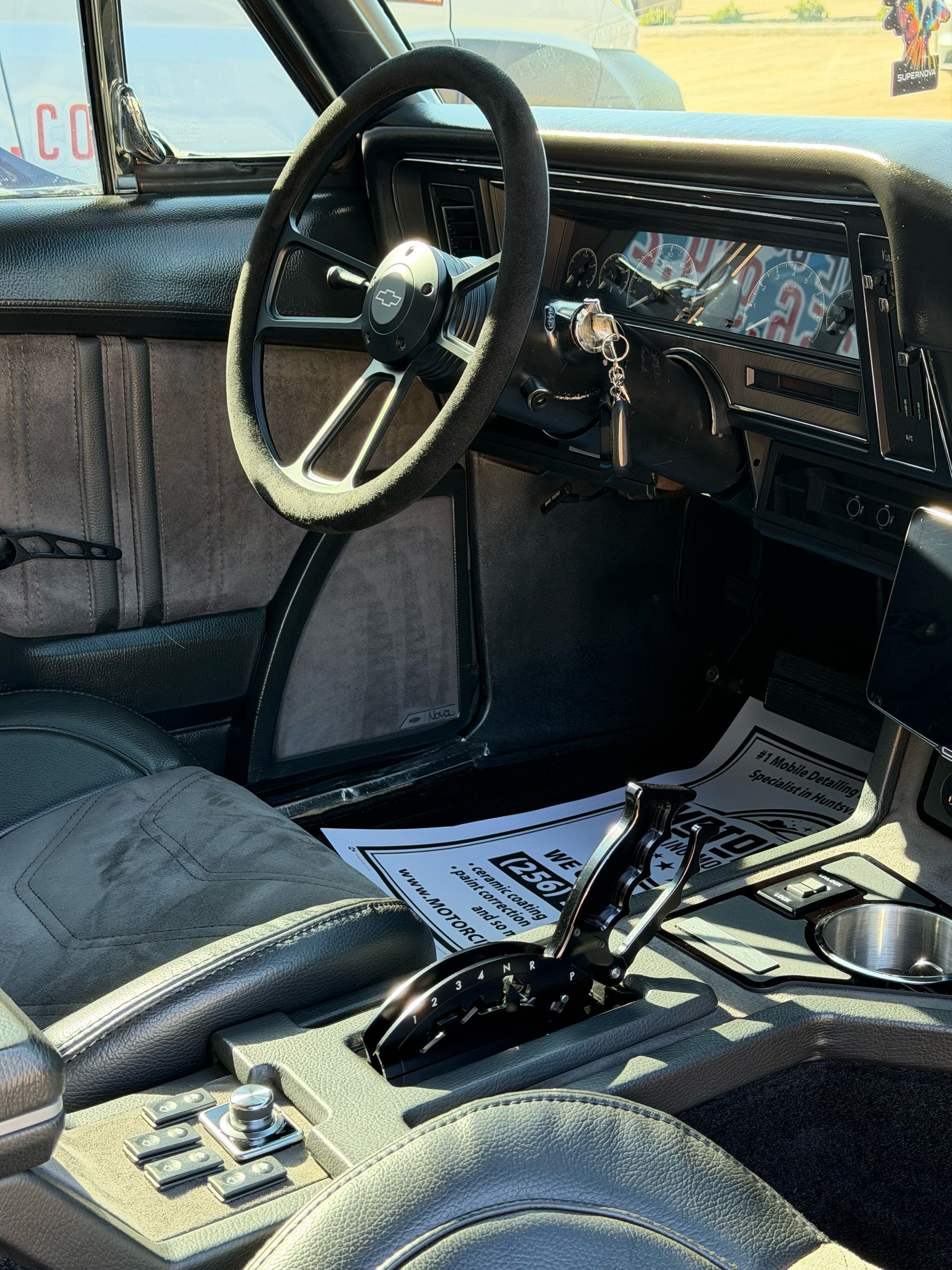 Car interior with black seats, steering wheel, dashboard, and gear shift visible.