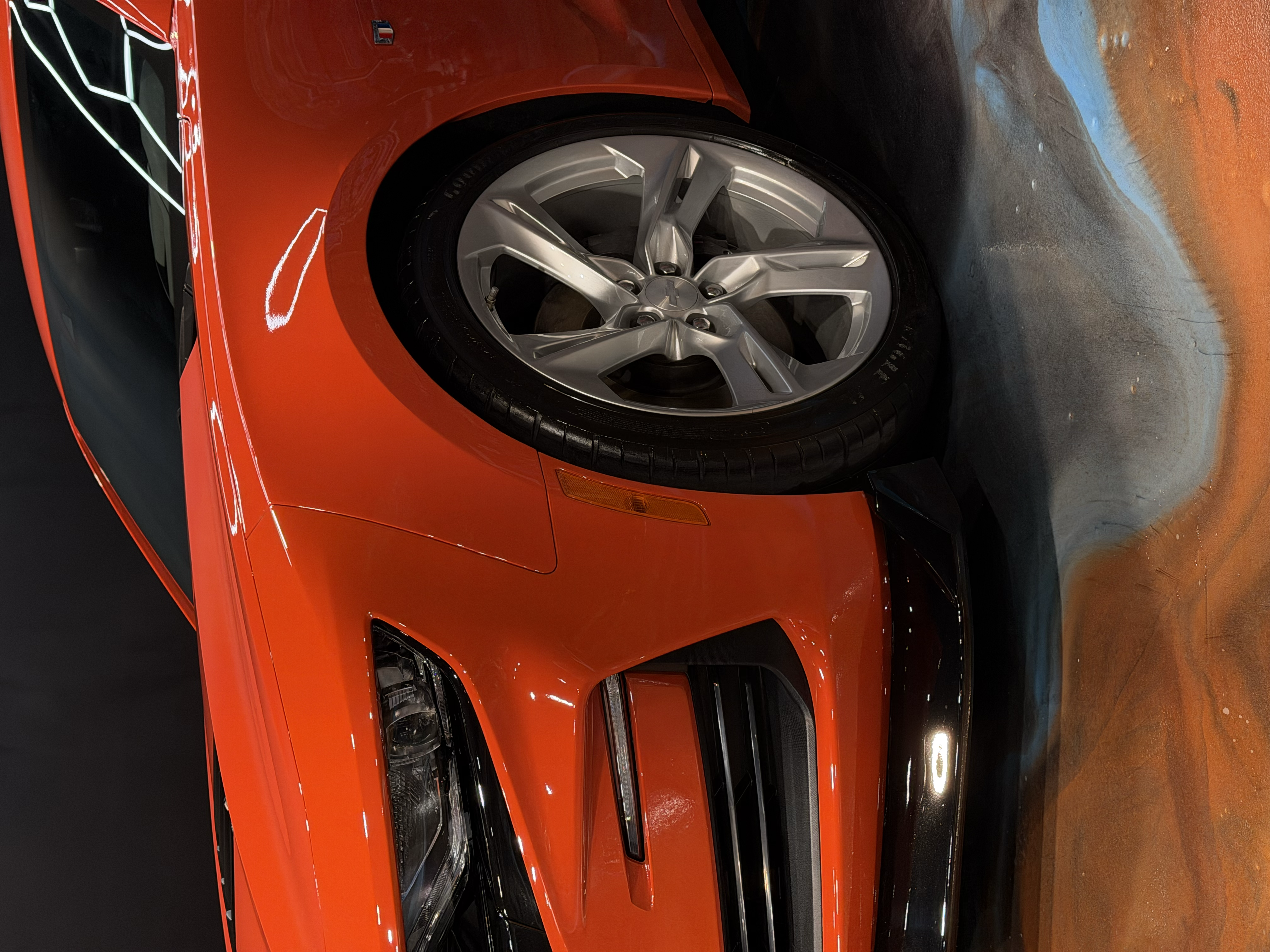 A man is washing a car with a brush in a garage.