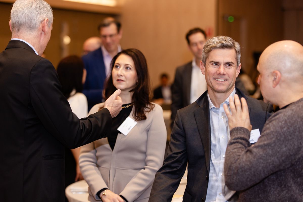 People in business attire talking at a networking event indoors