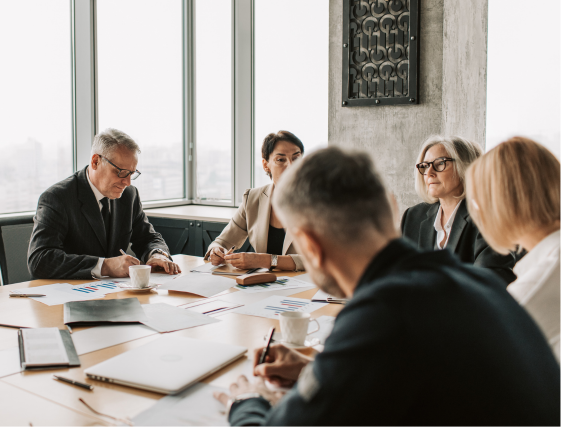 Small meeting group around a table reviewing papers in a bright office.