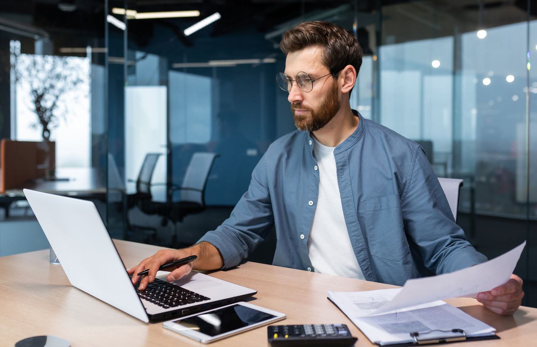 Person working at a laptop and reviewing papers in a modern office meeting room