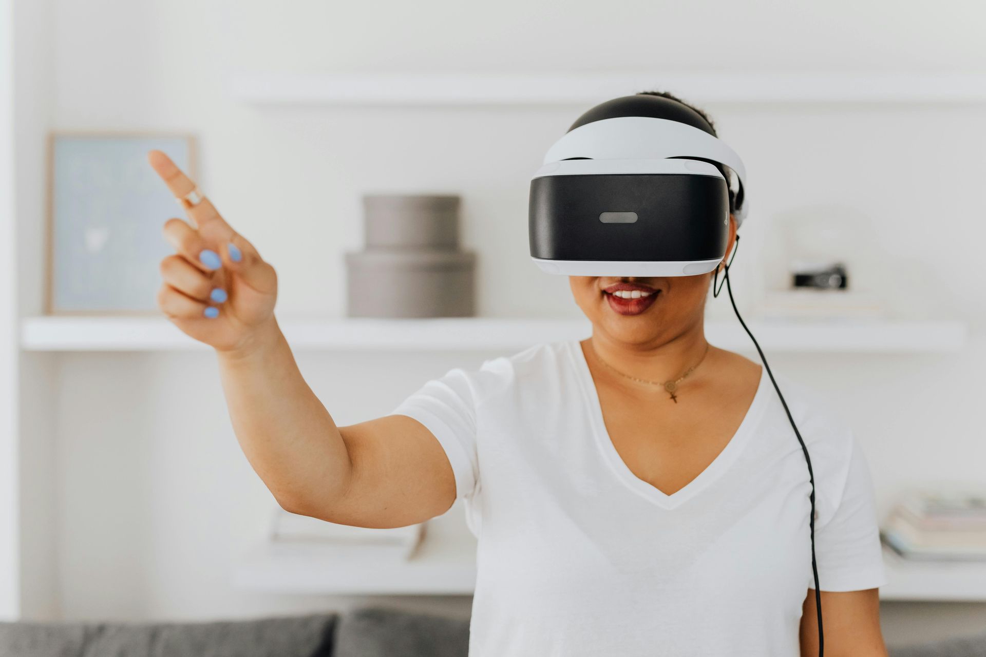 Person wearing a VR headset points in a bright room with shelves in the background
