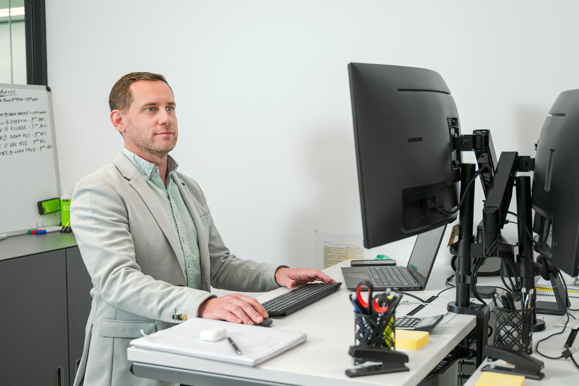 Man sitting at a desk working on a computer in a bright office