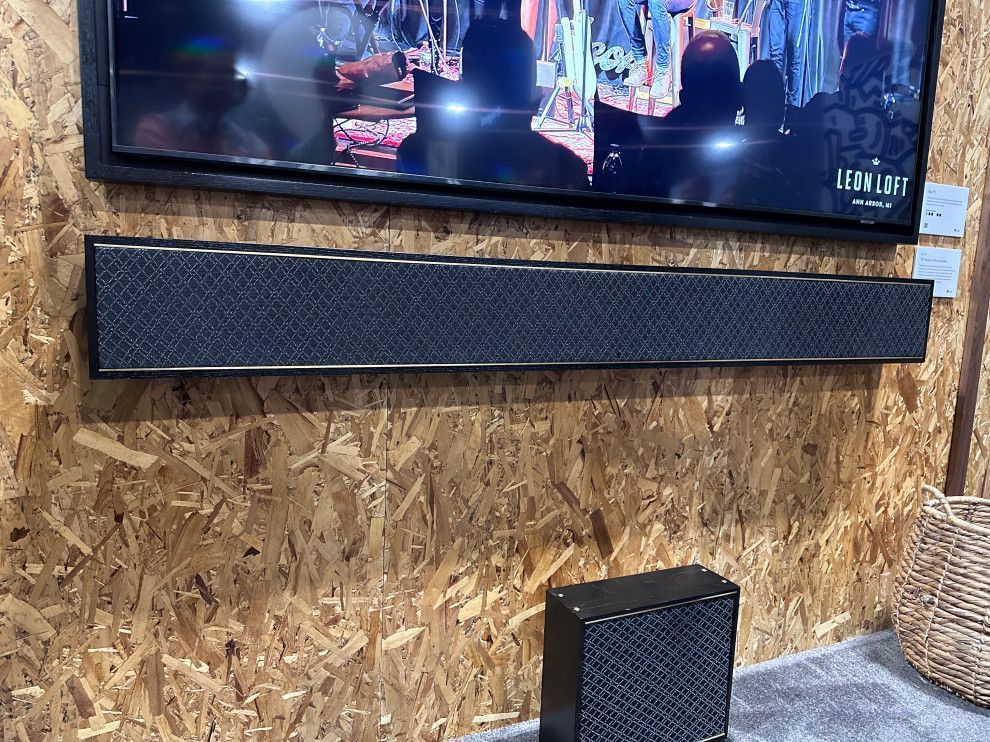 A television is hanging on a wooden wall next to a speaker.