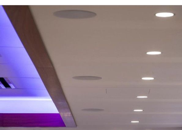 White ceiling with recessed speakers and lights. Section of purple and wood trim visible.
