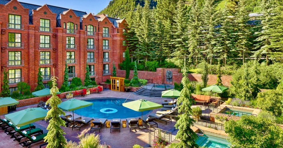 A large brick building with a swimming pool and umbrellas in front of it.