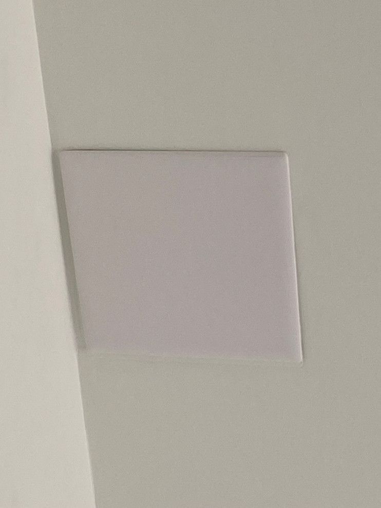 A square speaker is mounted to the ceiling of a room.