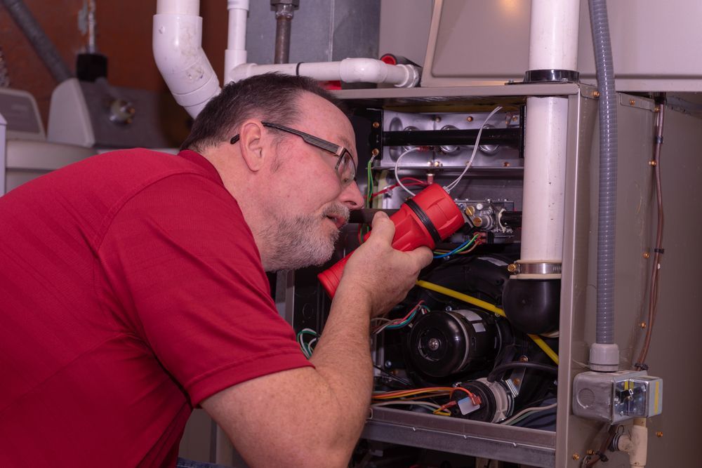 Man examining a furnace with a red flashlight.