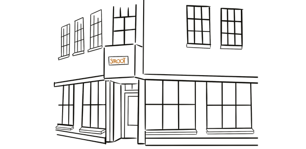 Een bakstenen winkelpui op een regenachtige hoek, met verlichte ramen en een voorbijganger.