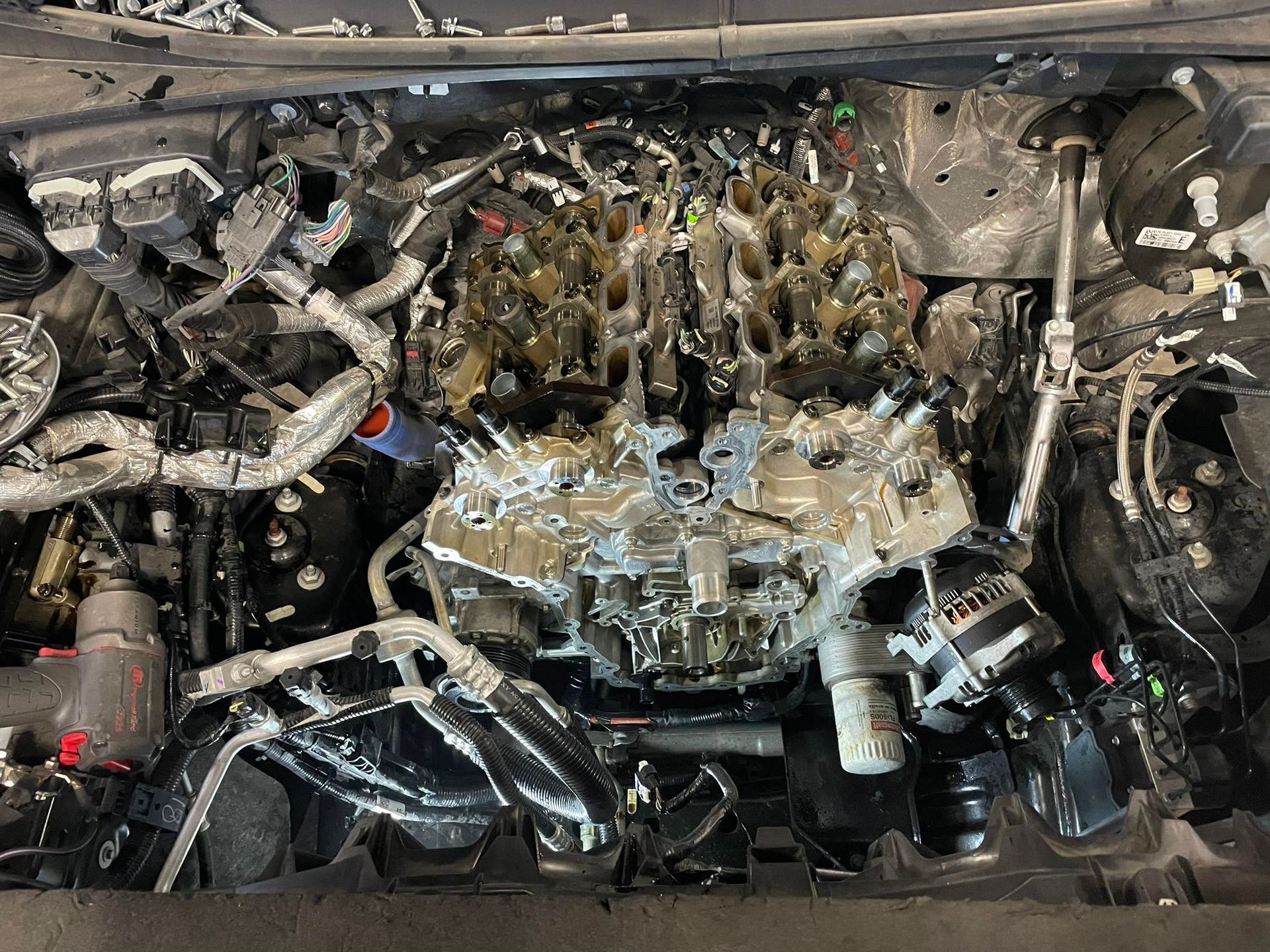 Exposed car engine bay with hoses and metallic parts, viewed from above | Proving Ground Automotive