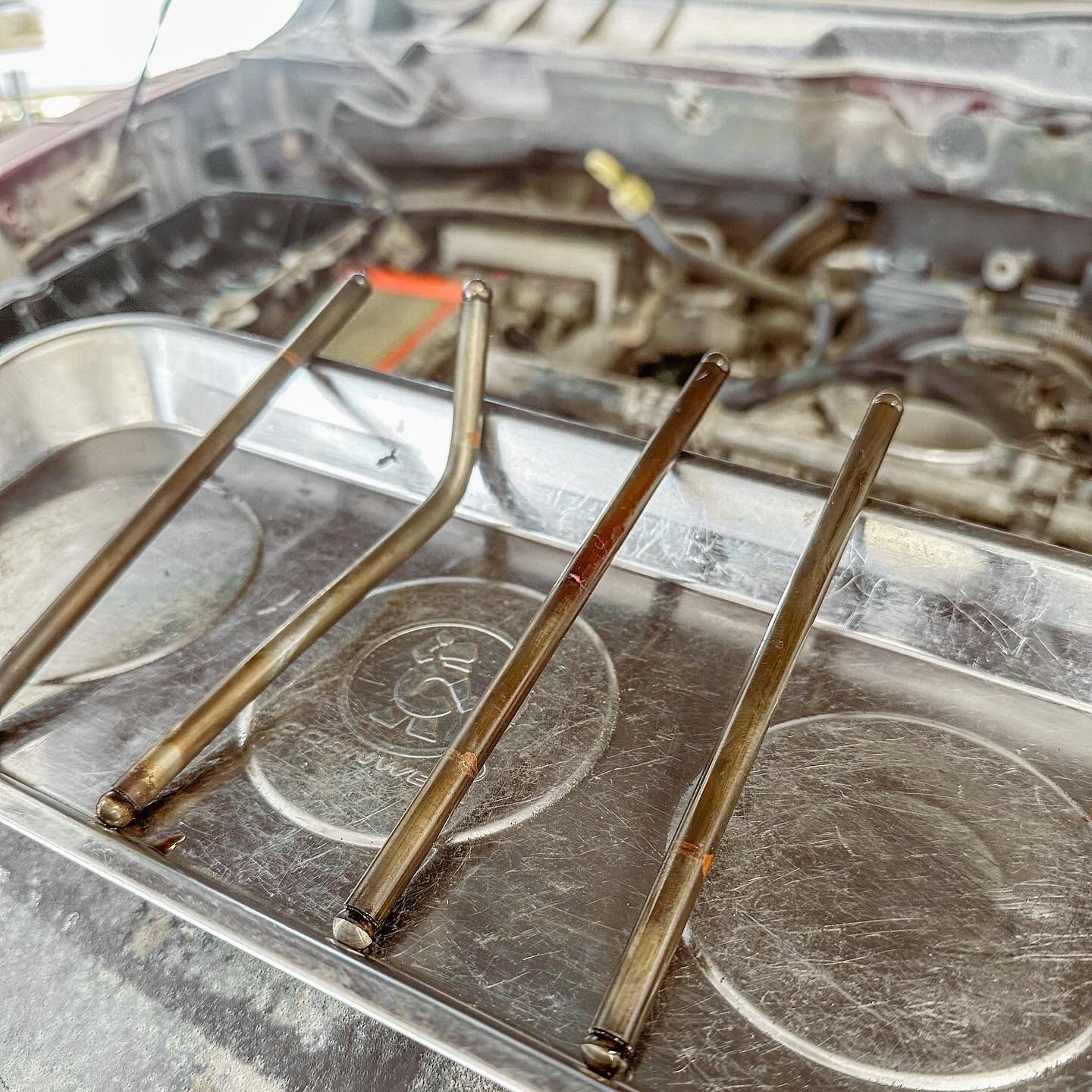 Close-up of a car engine bay with a metal tray and several thin rods laid across it. | Proving Ground Automotive