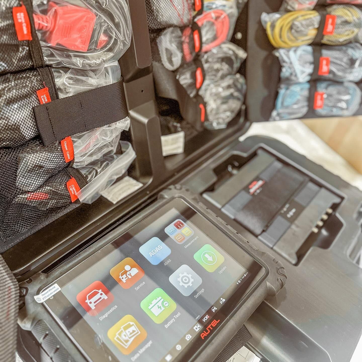 Portable diagnostic tablet and neatly arranged tool kits in a workshop display cabinet. | Proving Ground Automotive