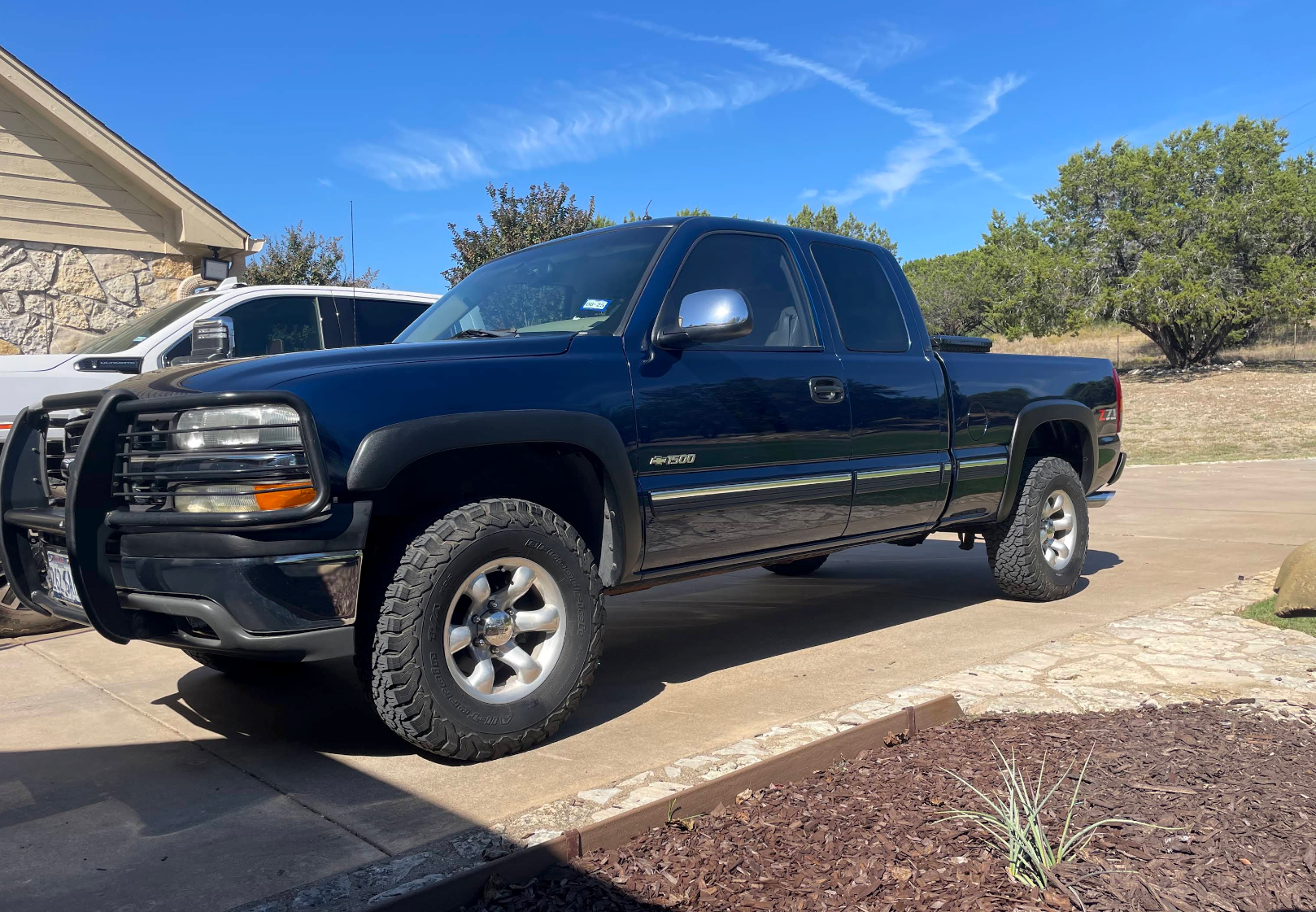 Black pickup truck parked in a driveway beside a house on a sunny day | Proving Ground Automotive