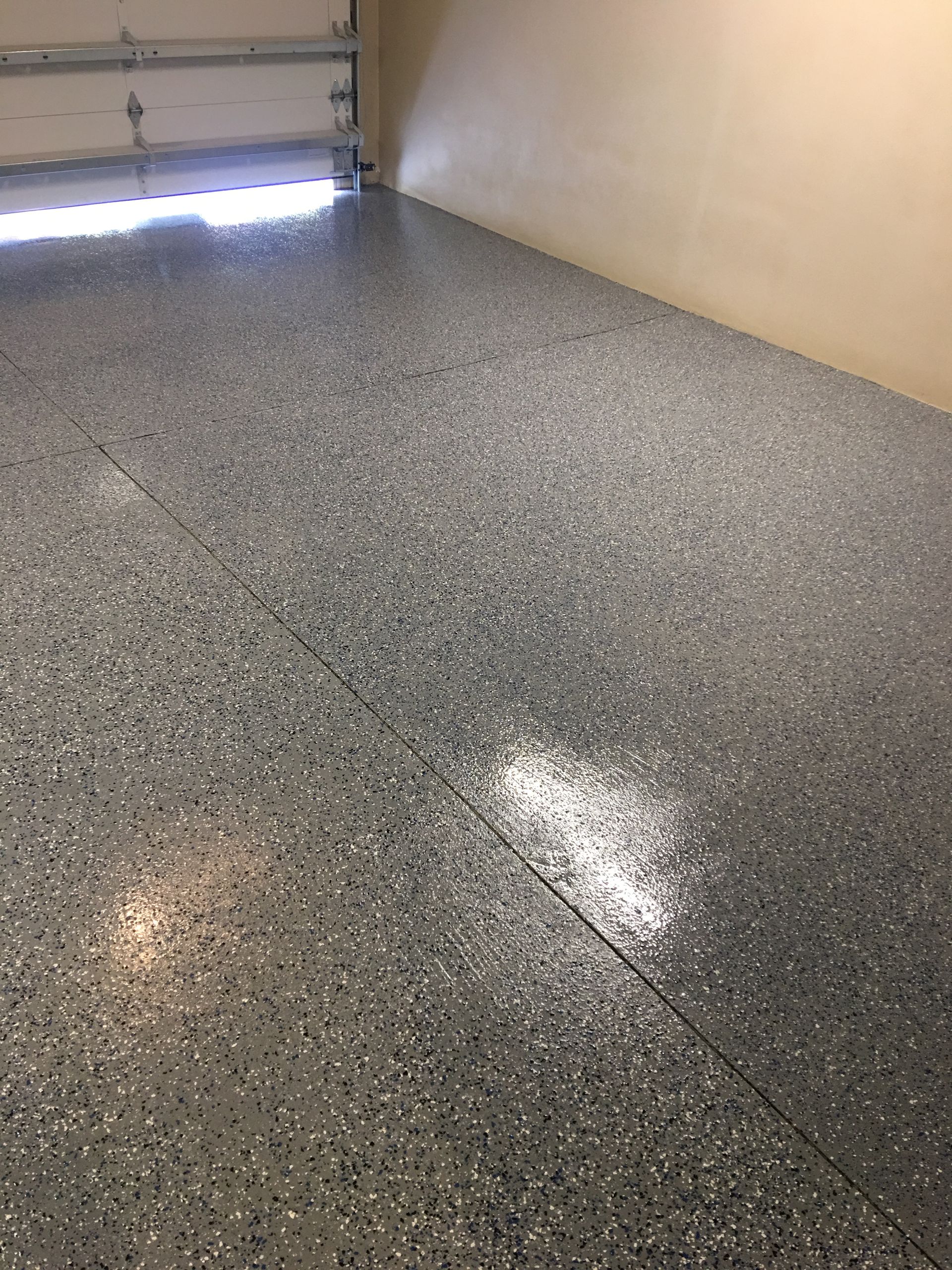 A garage with a shiny gray floor and a garage door.