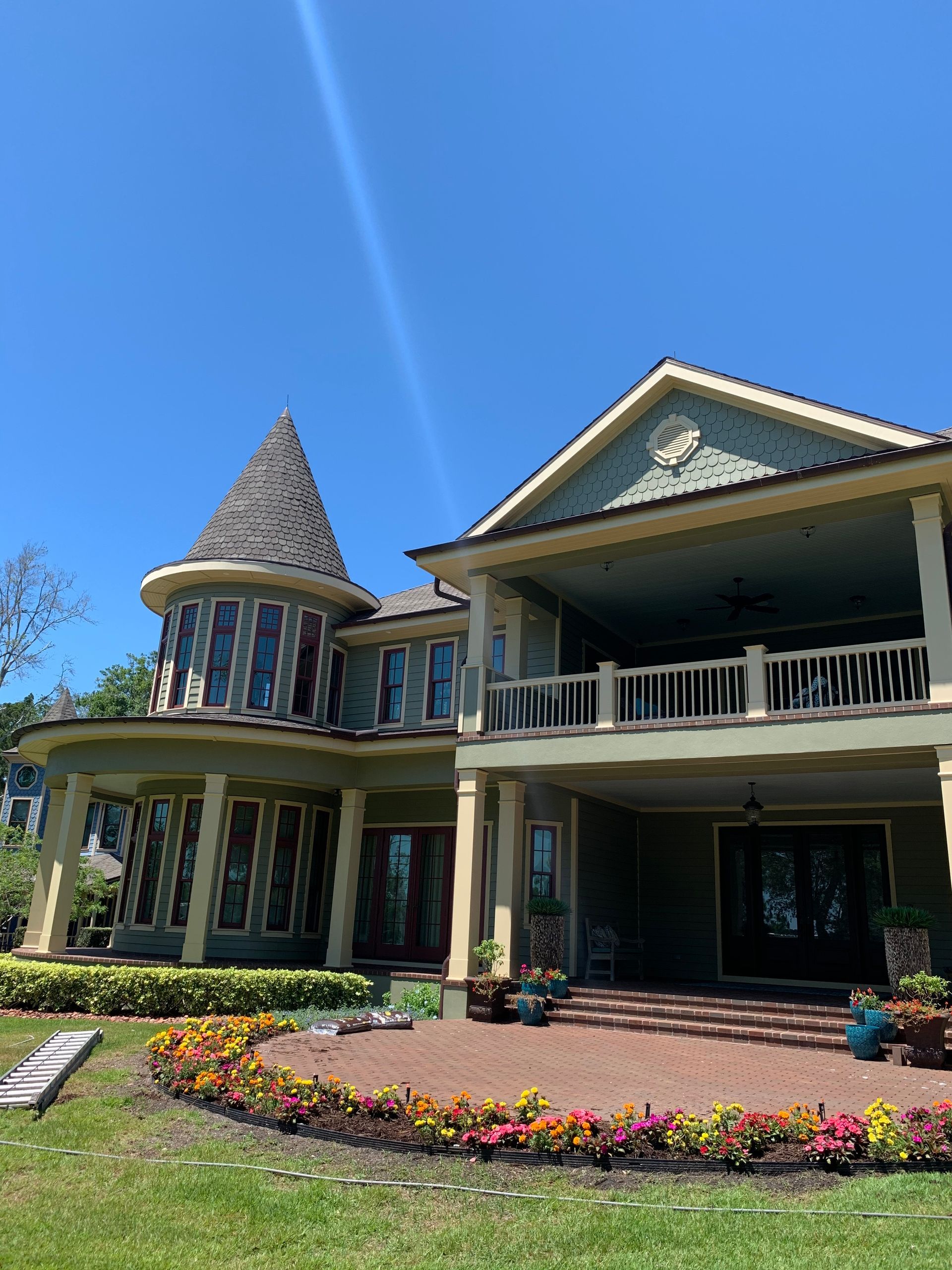 A large house with a tower on top of it is sitting on top of a lush green lawn.