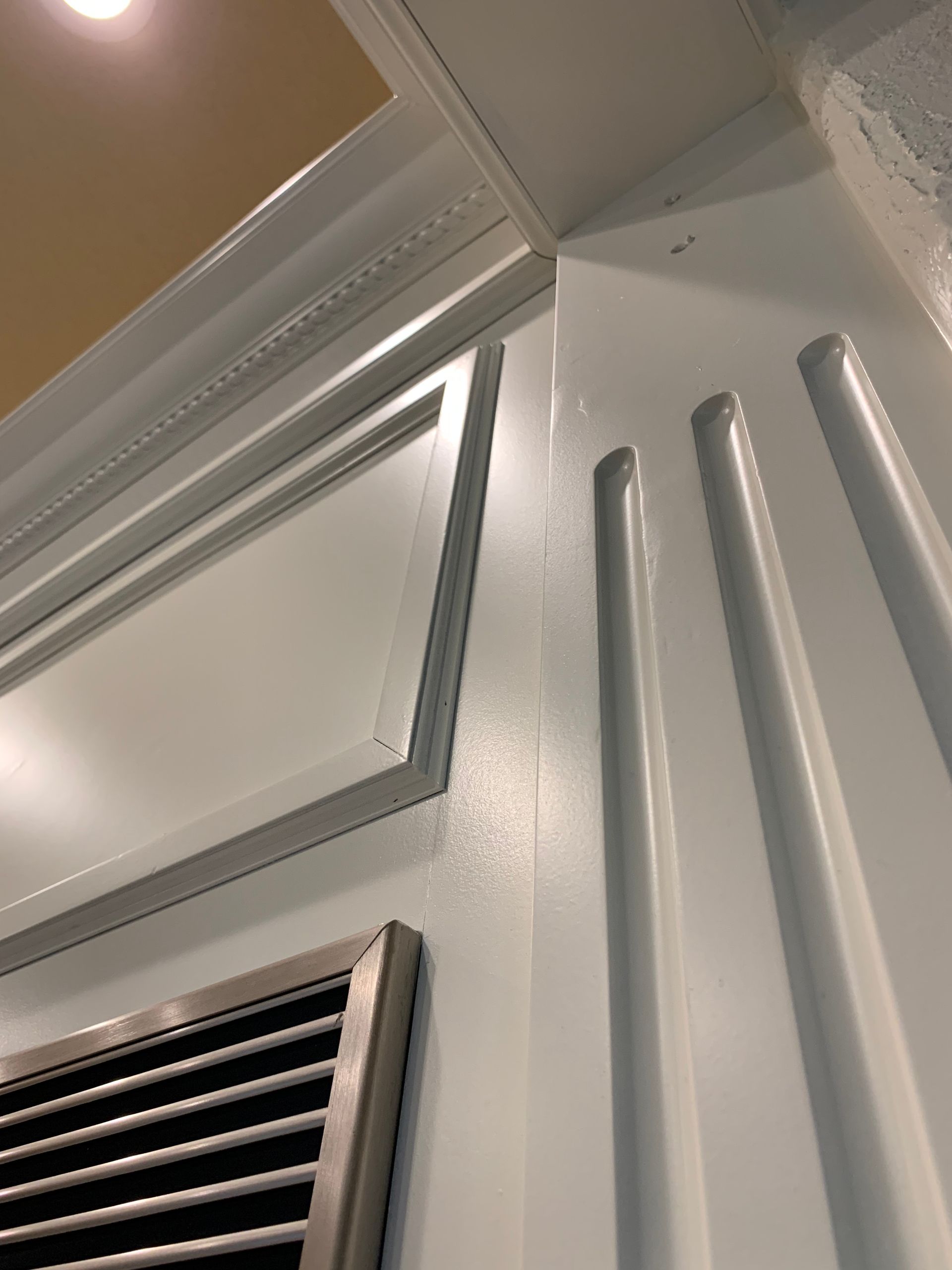 A close up of a white wall with a vent on it.
