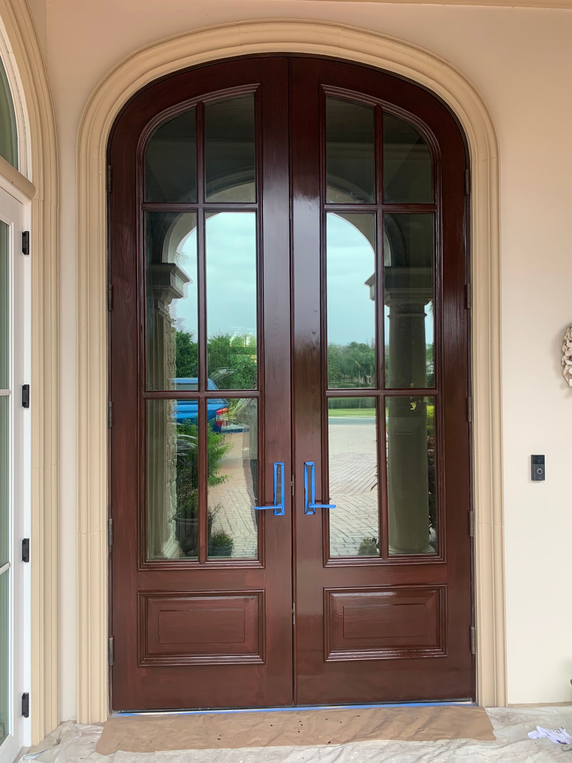 A large wooden door with arched windows is in a house.