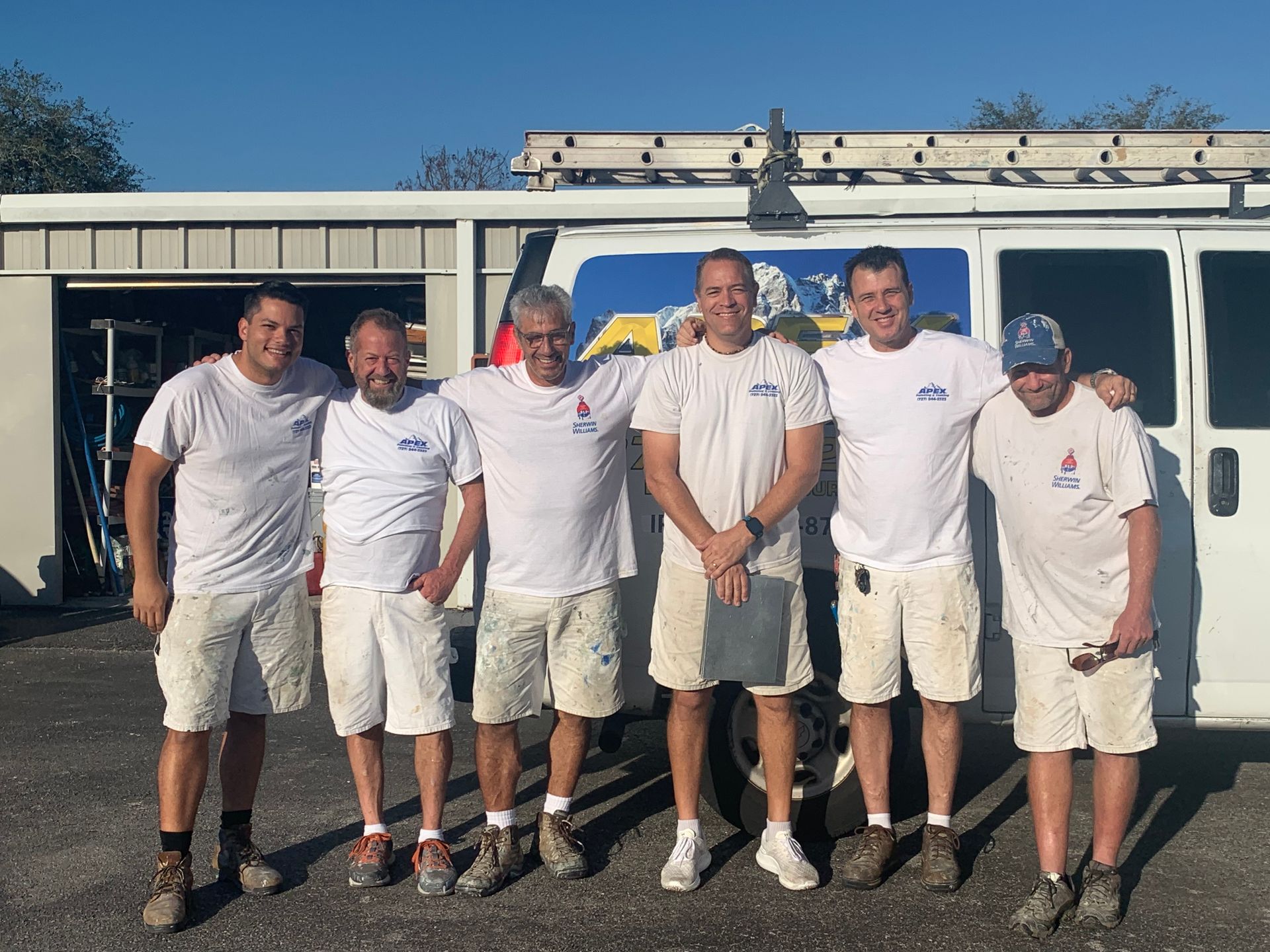 A group of men are posing for a picture in front of a van.
