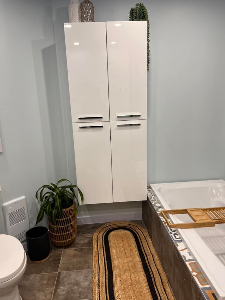 Une salle de bains moderne avec une haute armoire blanche, une baignoire et un tapis en jute.