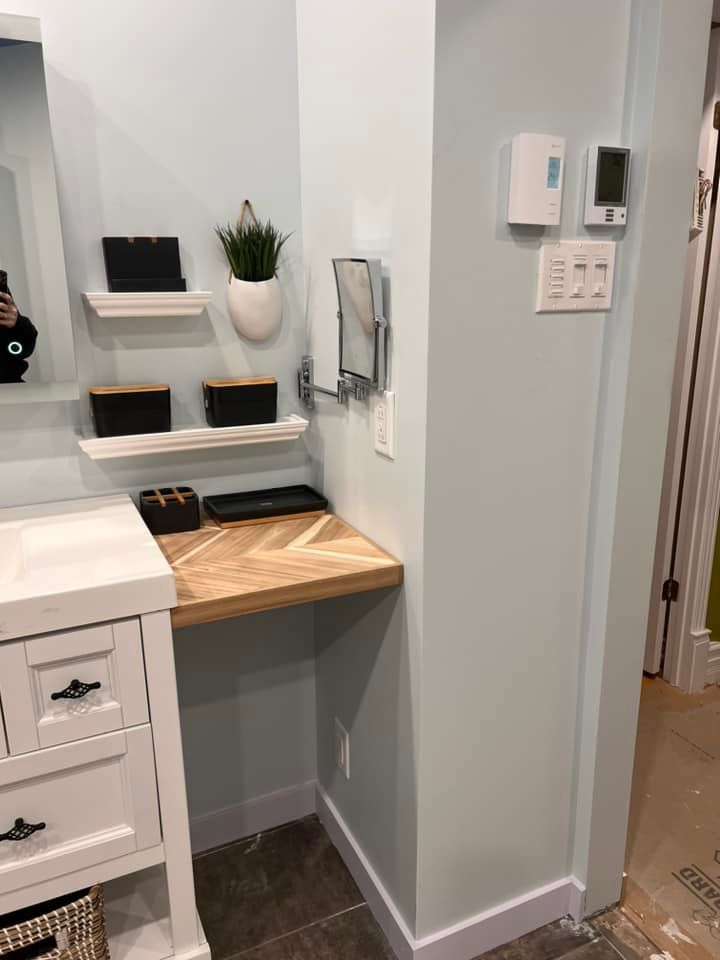 Salle de bains avec meuble-lavabo blanc, petit bureau en bois et miroir mural. Murs bleu clair.