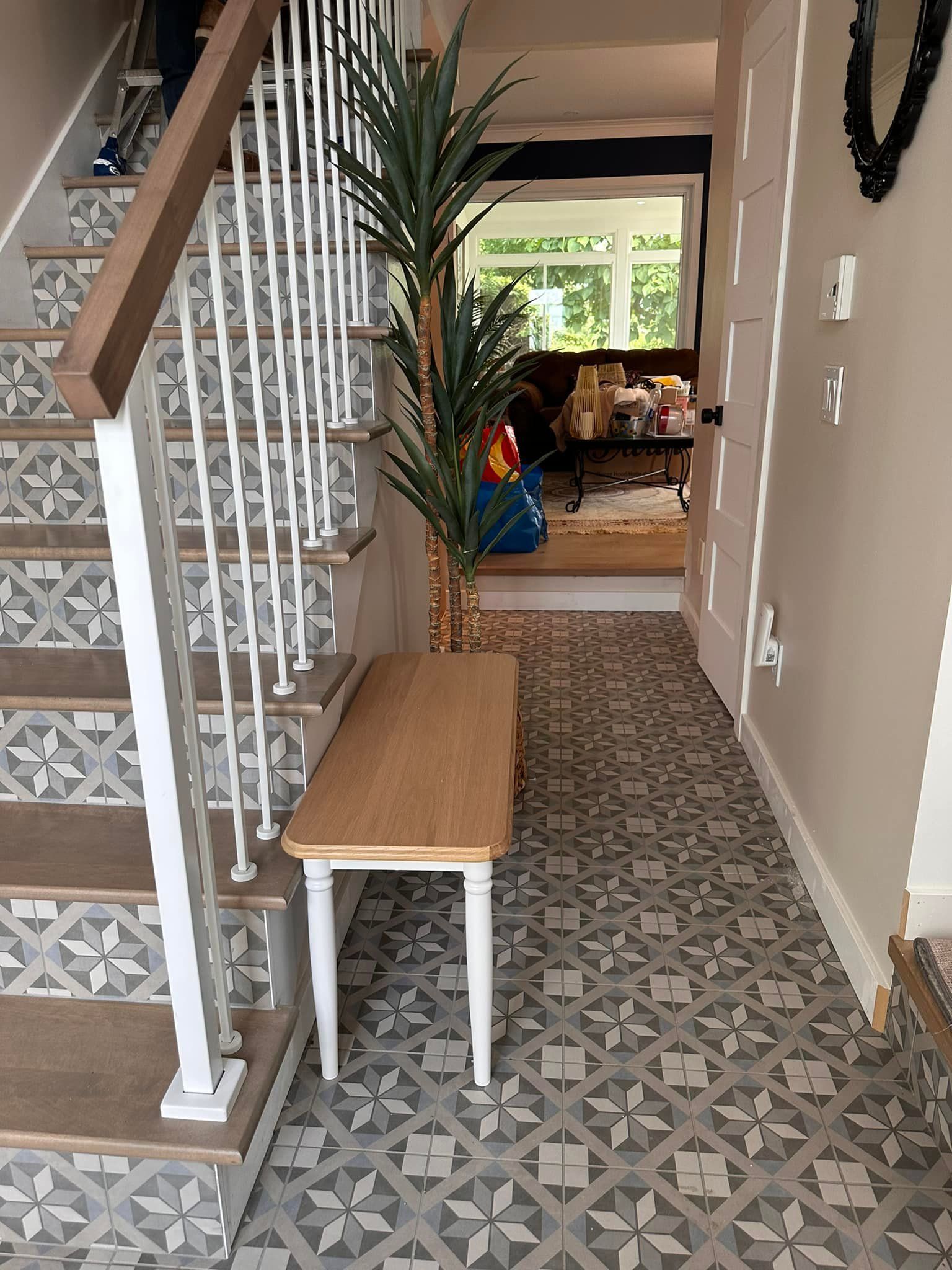 Entrée avec sol carrelé à motifs, banc en bois et escalier avec contremarches à motifs d'étoiles.
