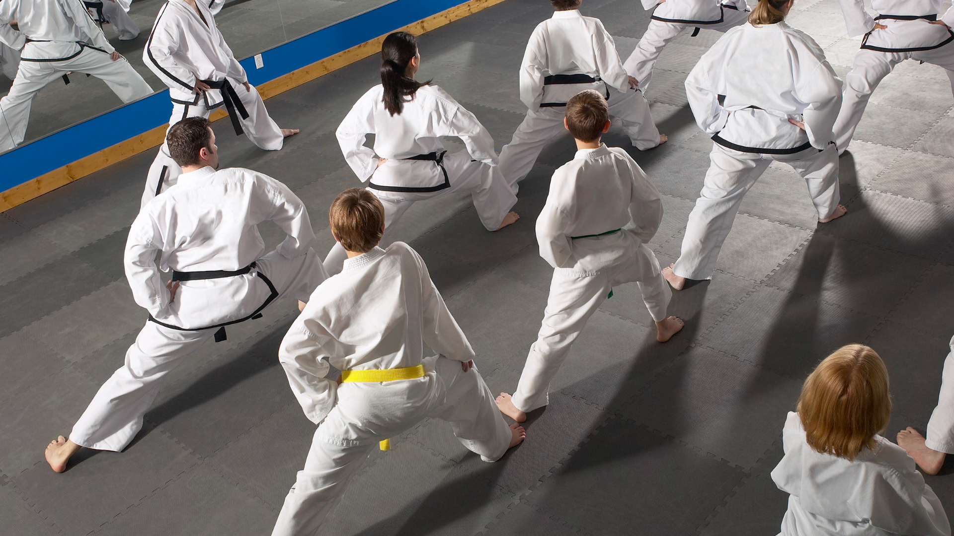 A group of people are practicing karate in a gym.