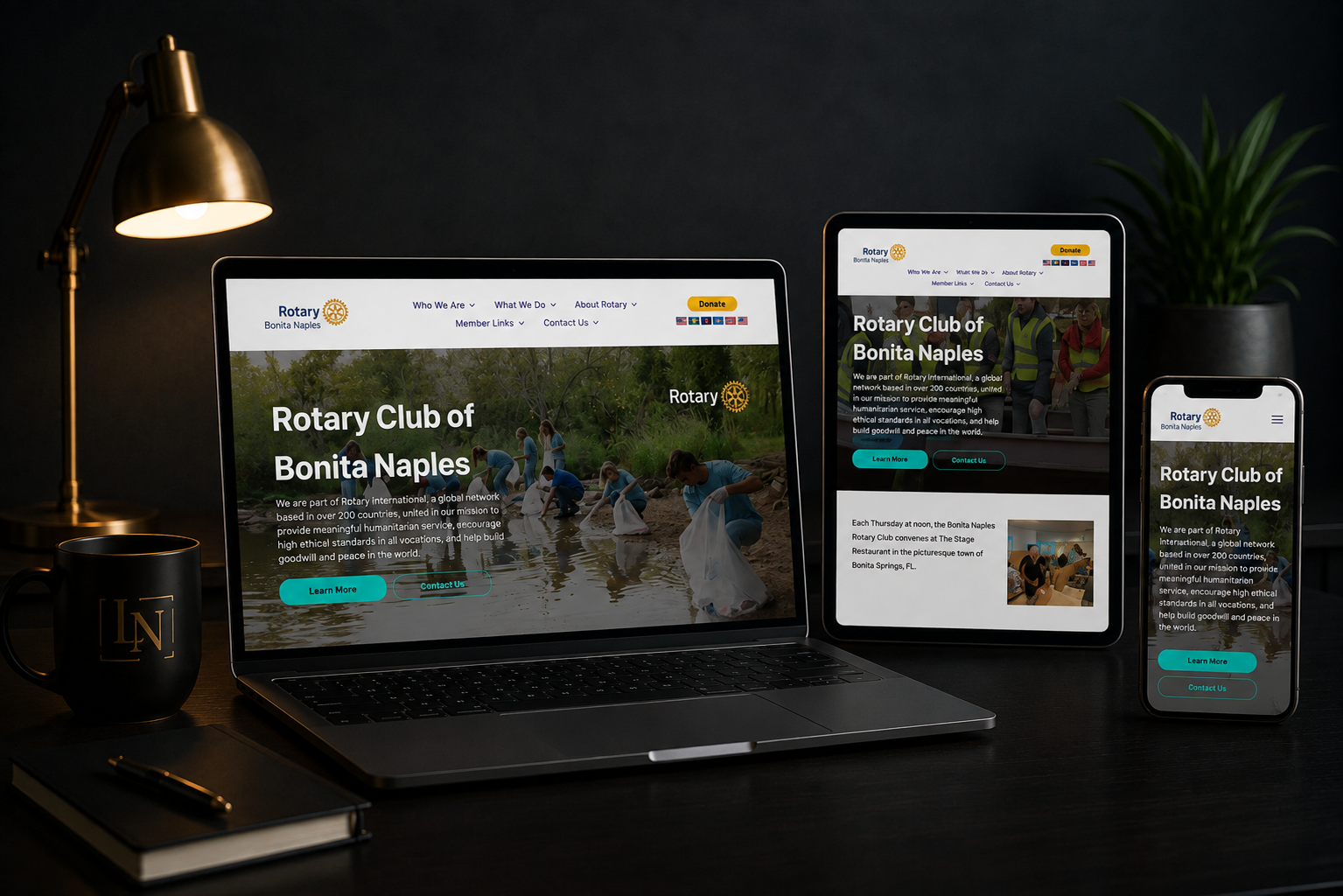 Desktop, laptop, tablet, and phone displaying Rotary Club of Bumi Napi's website on a dark desk
