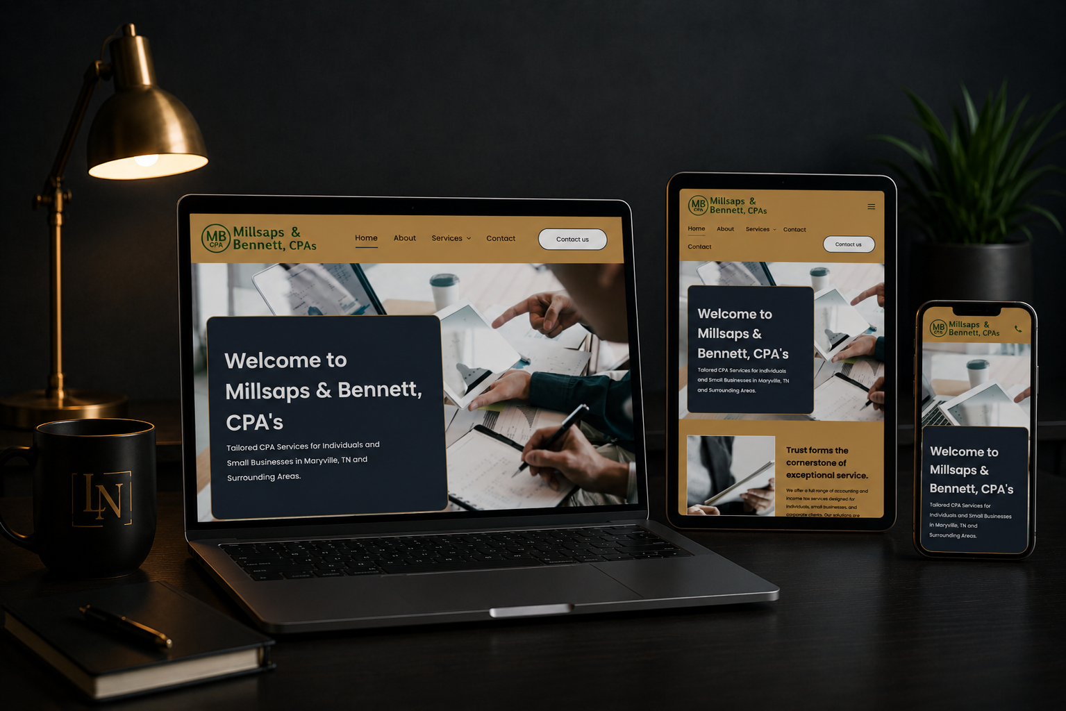 Laptop, tablet, and phone displaying a dark-themed website mockup on a desk with a lamp and plant.