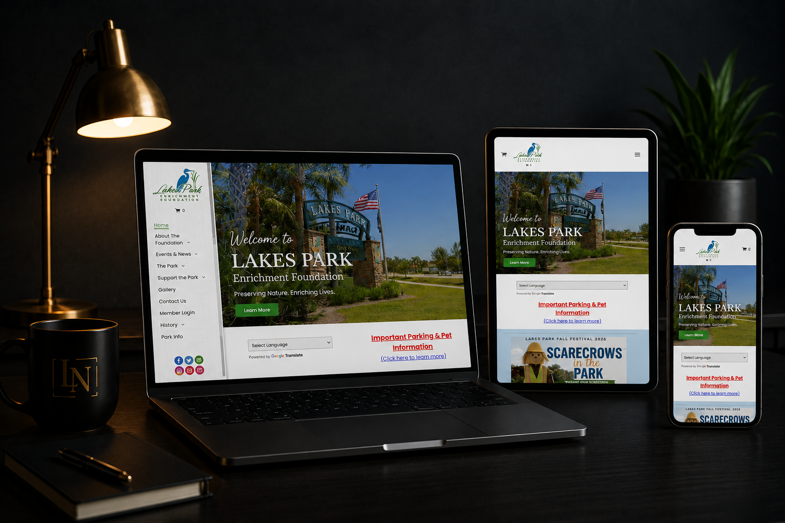 Responsive website displayed on laptop, tablet, and phone on a dark desk with lamp and plant