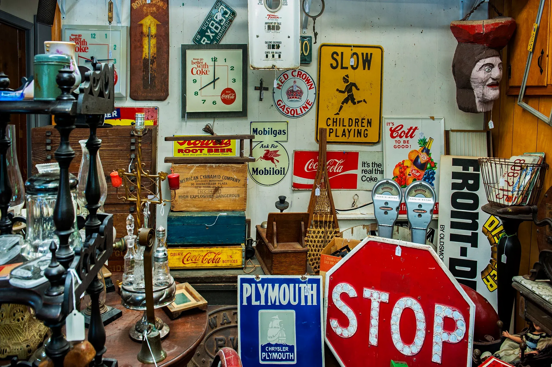 An indoor shop filled with vintage signs, road markers, old crates, and various antique collectibles.