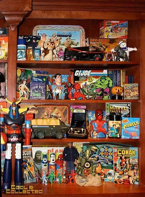 Wooden shelves display a large collection of vintage toys, action figures, board games, and comic books.