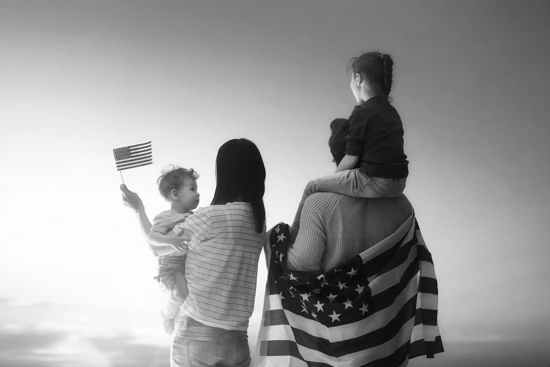 Family with two children celebrating, draped in and waving US flag.