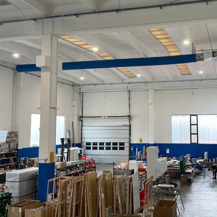 Interieur van een magazijn met hoge plafonds, textiele luchtverdeelslangen & airsocks, een grote roldeur en diverse objecten die er verspreid liggen.