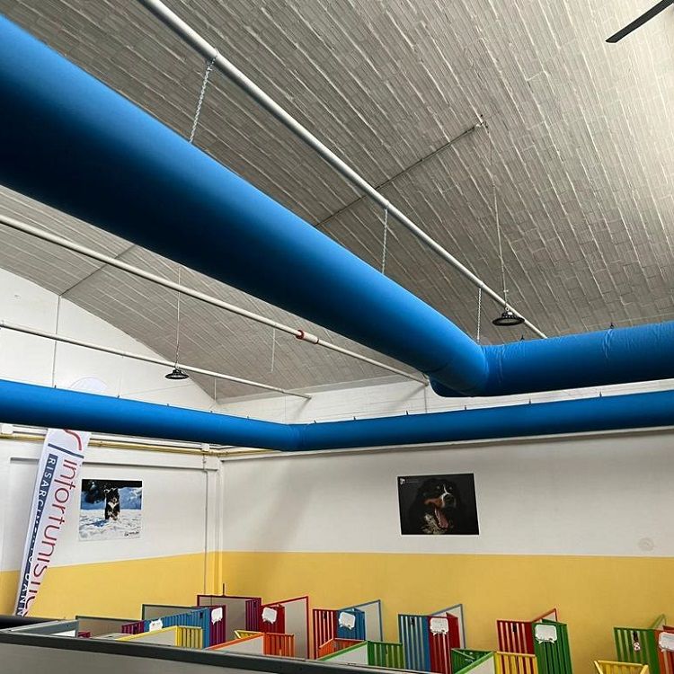 Blauwe textiele luchtverdeelslangen & airsocks in een gebouw met een wit plafond en kleurrijke trainingshindernissen.