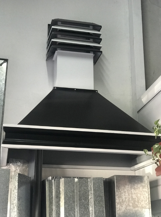Campana extractora negra montada en la pared sobre una estufa en una cocina moderna.