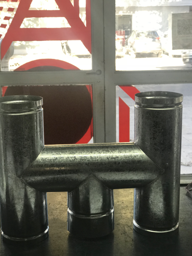 Barrera metálica con tres postes cilíndricos negros frente a una ventana con marcas geométricas rojas y blancas.
