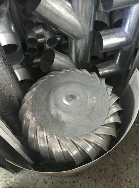 Álabes de turbina metálicos y piezas mecanizadas circulares apiladas en un contenedor.