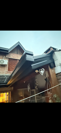 Exterior de una casa de madera con tejado a dos aguas y decoración en forma de corazón, vista bajo un tejado de porche inclinado con luz lluviosa.