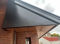 Toldo negro moderno sobre una puerta de ladrillo con detalles de plafón de madera.