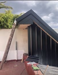 Techo de una casa dañado con una escalera apoyada contra la pared y materiales de construcción en un patio.