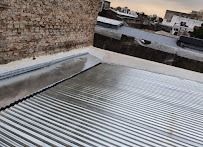 Azotea con techo de chapa ondulada, pared de ladrillo y edificios de la ciudad a lo lejos al atardecer.