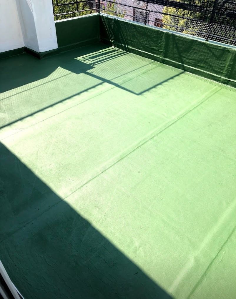Suelo de patio verde al aire libre con barandilla que proyecta sombras y luz solar.