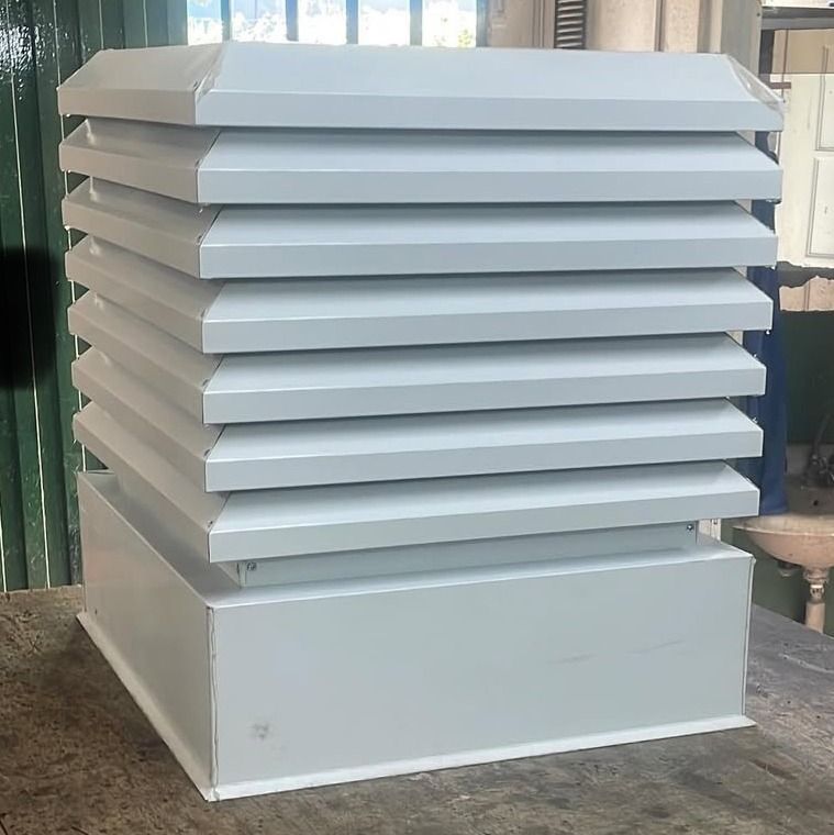 Conjunto de rejillas de ventilación blancas o unidades de climatización (HVAC) apiladas en el exterior sobre un suelo de hormigón.