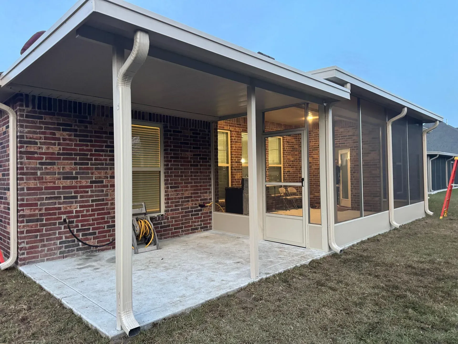 Back patio with brick wall, covered porch, white columns, and sliding glass doors.