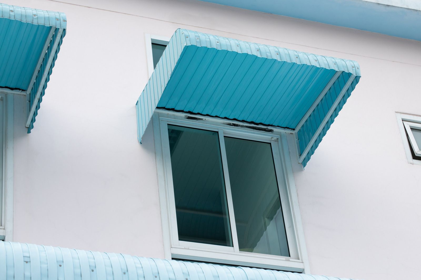 Blue awnings over windows on a light blue building facade