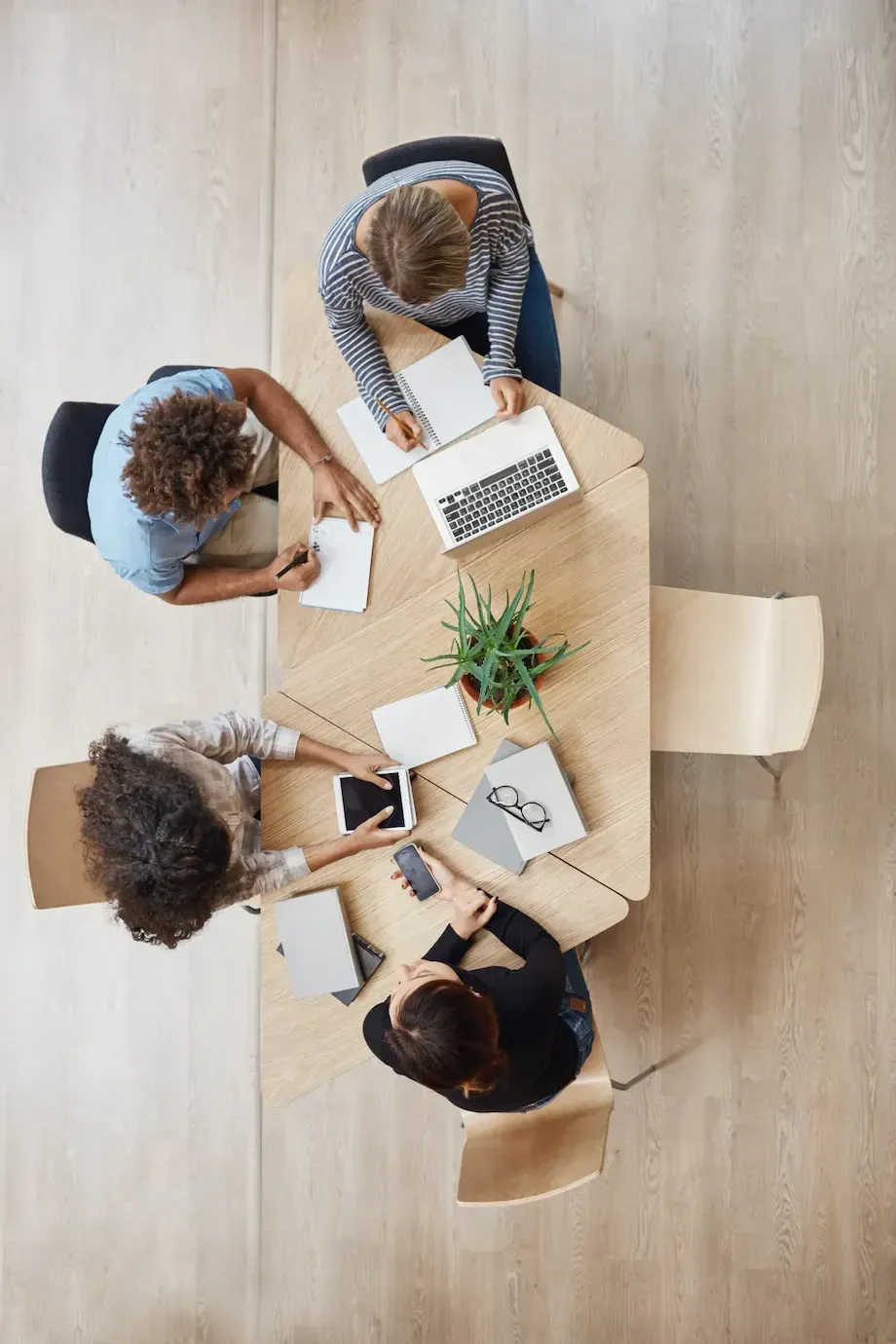 un grupo de personas se sienta alrededor de una mesa con una computadora portátil y una tableta