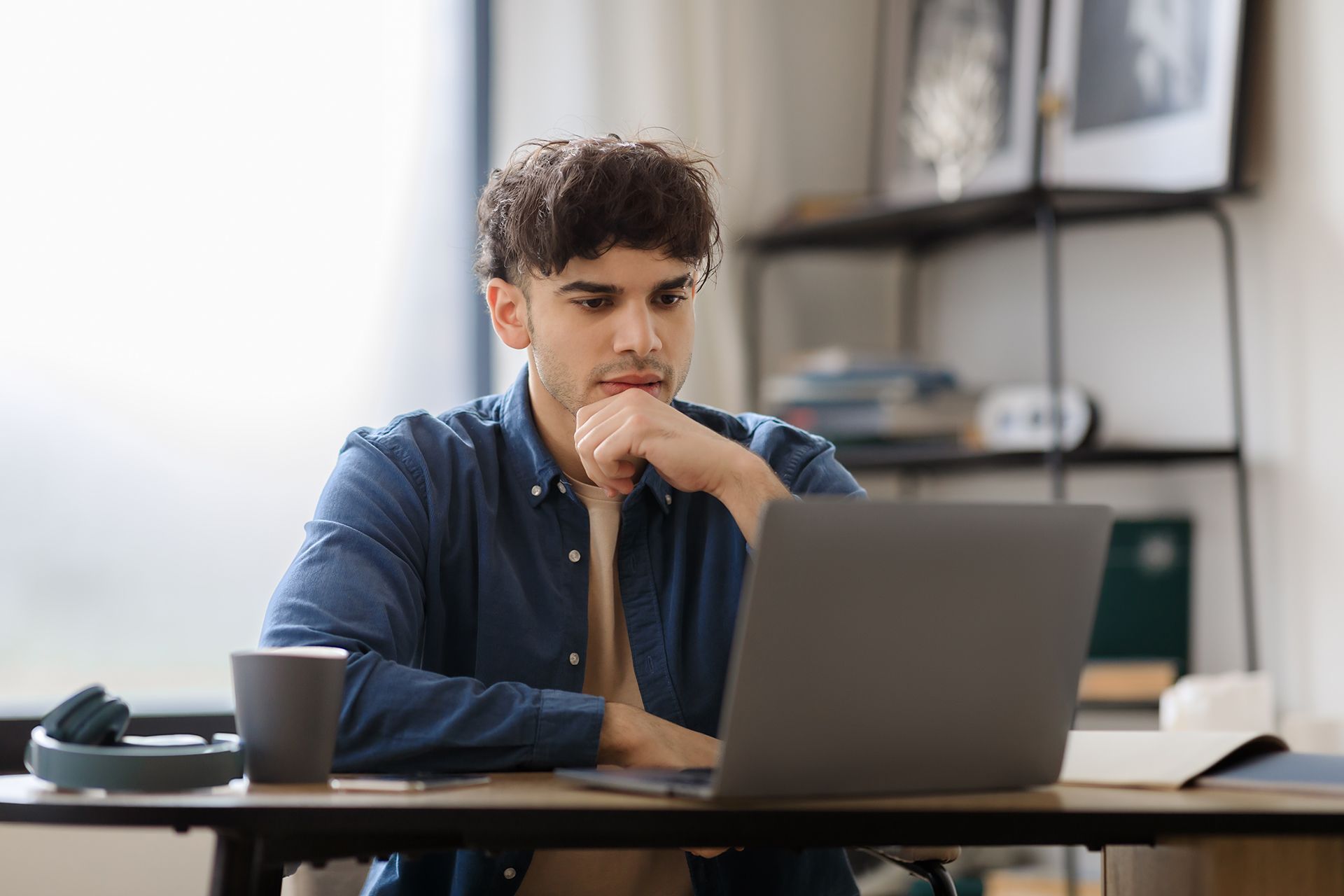a man is sitting at a desk using a laptop computer .