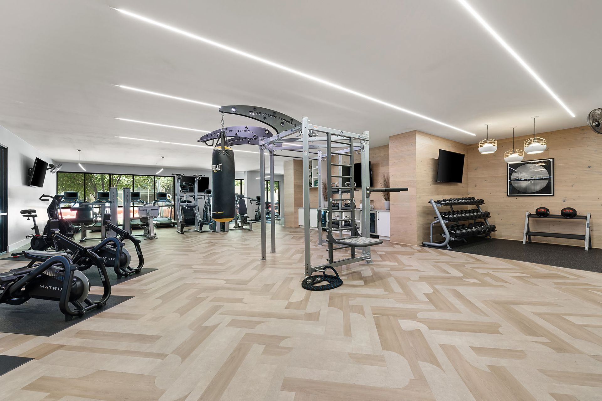 Modern gym interior with exercise machines, weights, and mirrored walls under bright ceiling lights