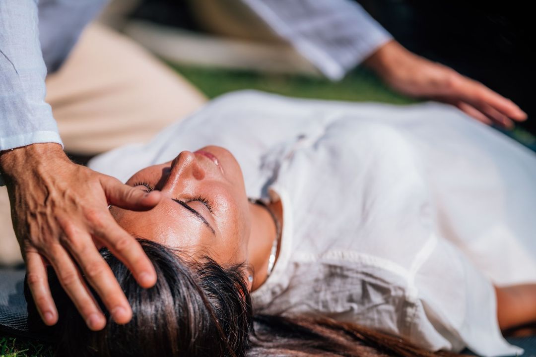 Person lying down while another hand rests on their forehead, suggesting a health check or soothing gesture